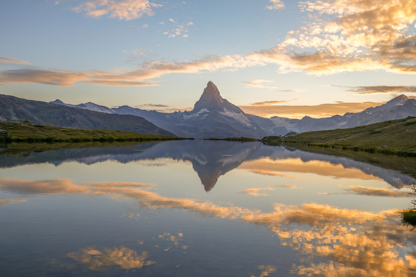 The Matterhorn glowing orange-pink at sunset, reflected in the Stellisee lake
